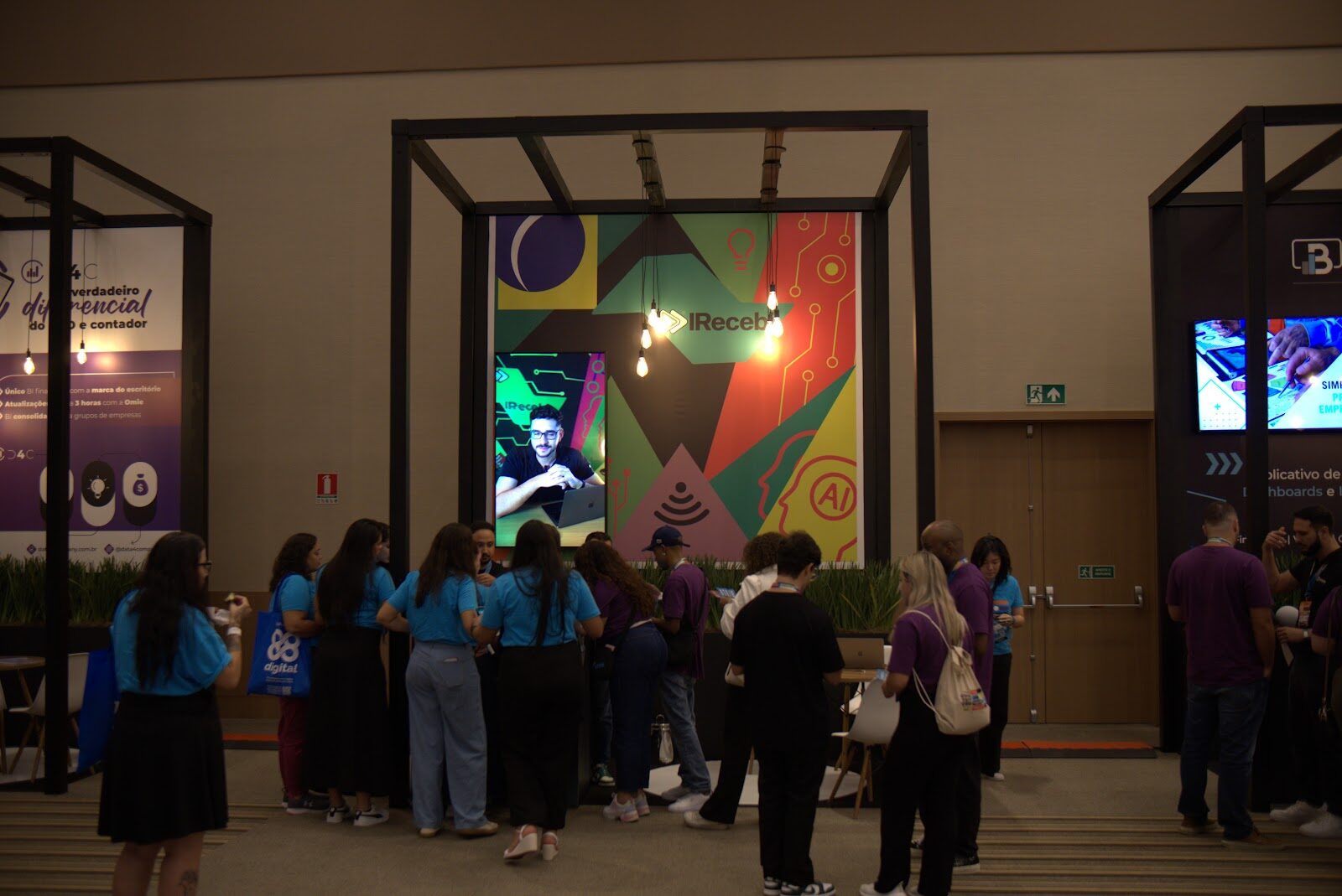 Telão LED na entrada de estande corporativo com visitantes reunidos em fila durante feira