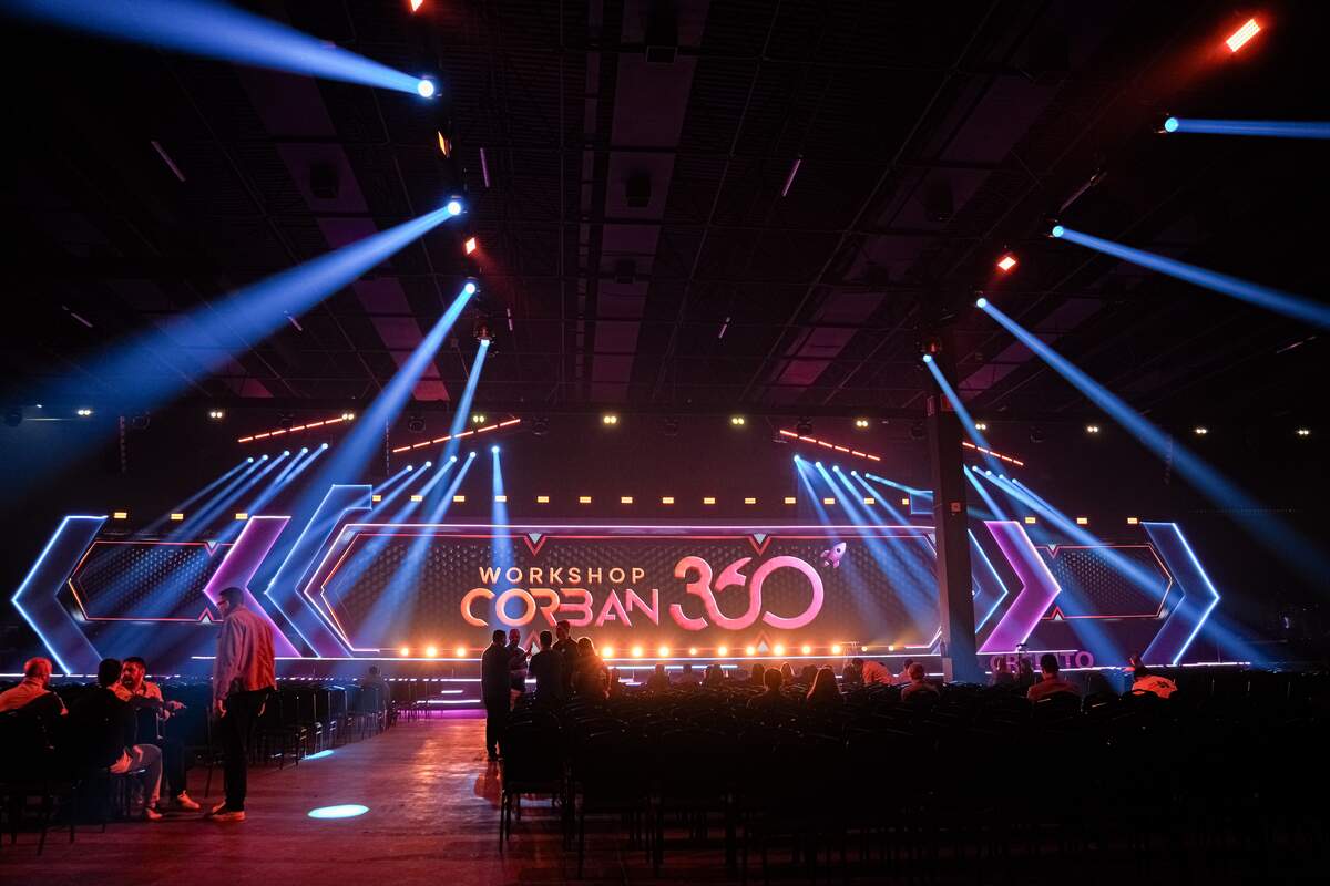 Palco de workshop corporativo com painel de LED e feixes de luz coloridos