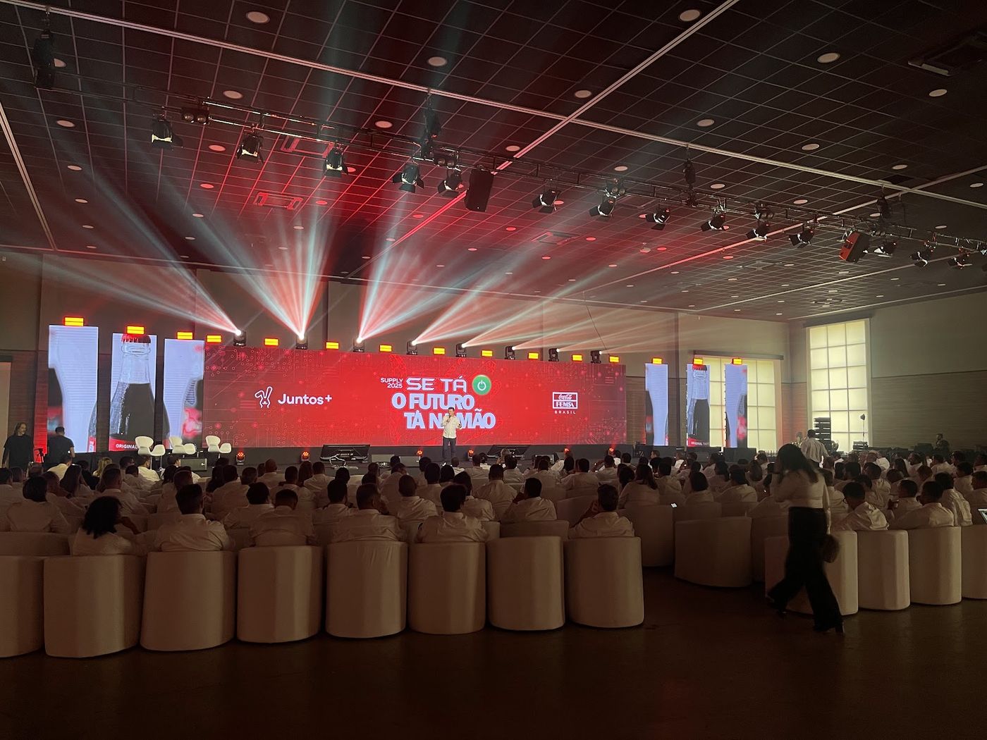 Convenção corporativa Femsa com painel LED vermelho, plateia sentada em pufes e iluminação cênica