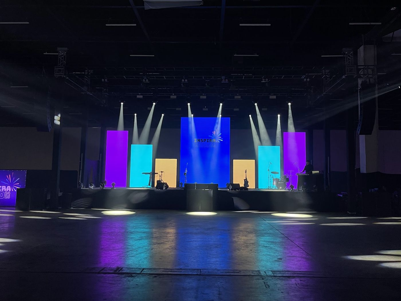 Palco corporativo com painéis LED, treliça metálica e caixas de som em galpão