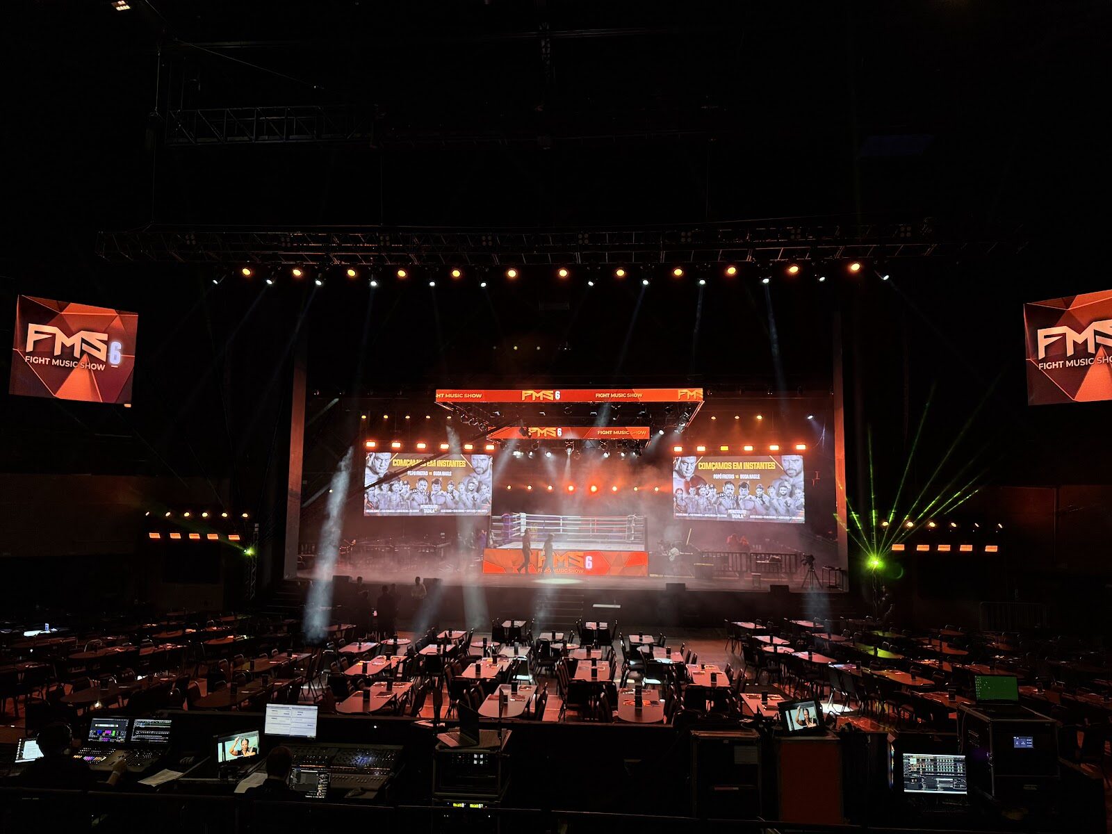 Palco de show com sistema de som, treliças e telões de LED vistos da mesa técnica